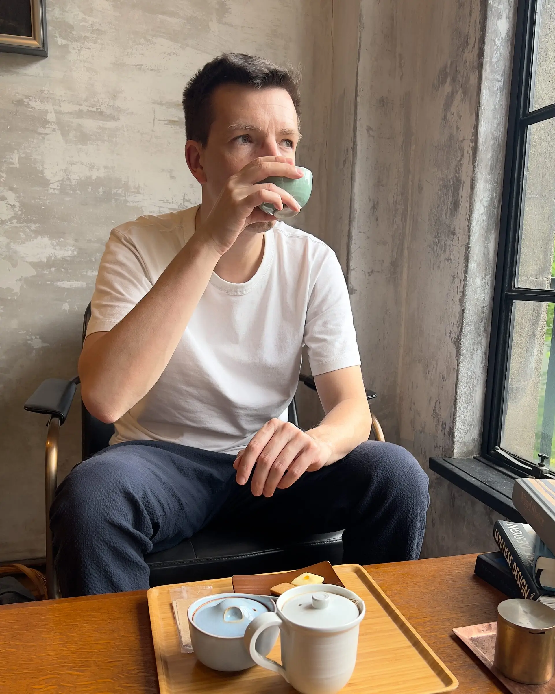 Camille Roux drinking tea by a window.