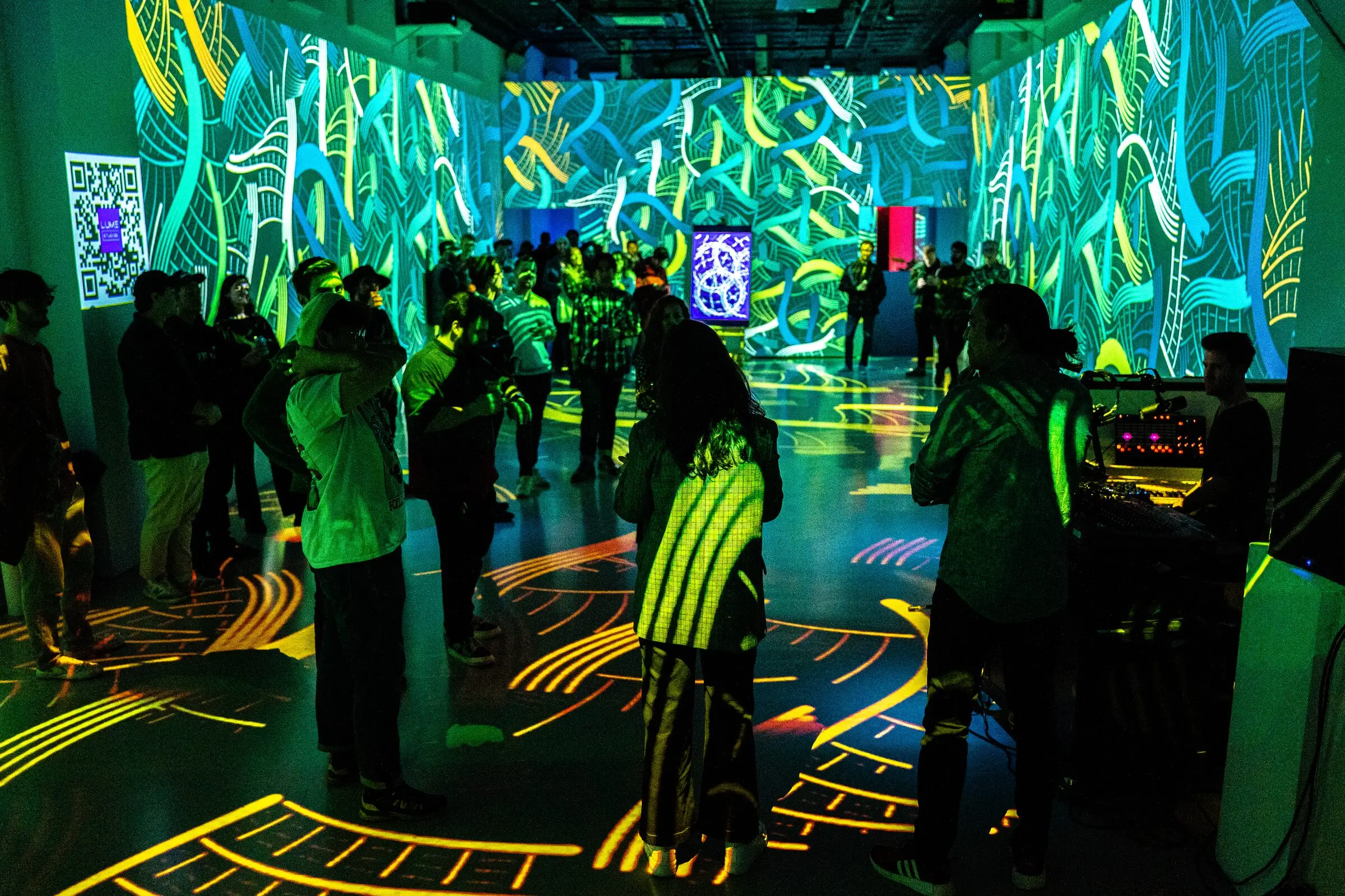 Visitors among green and yellow projections during the INTRICADA event, Lume Studios, New York.