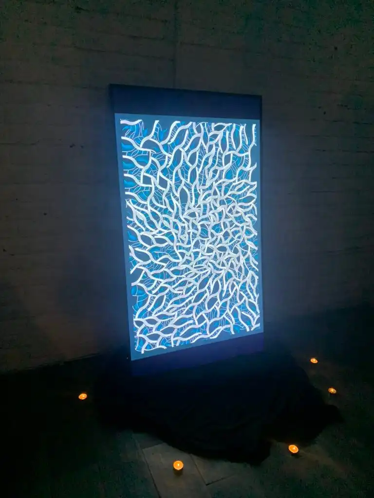 An INTRICADA screen on black fabric, surrounded by candles in a dark room, Bright Moments Mexico City.