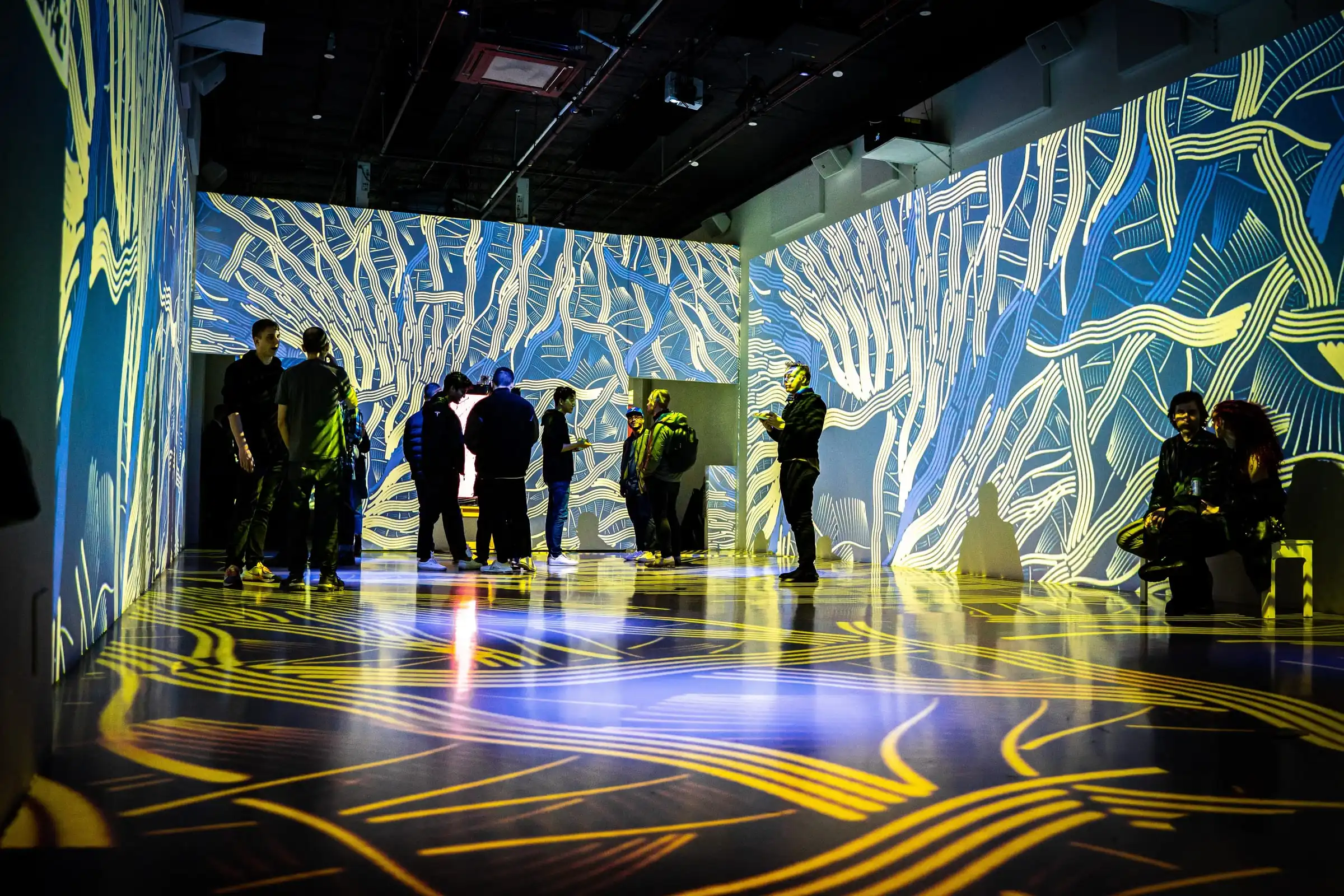 Visitors in a room of INTRICADA projections on walls and floor, Lume Studios, New York.