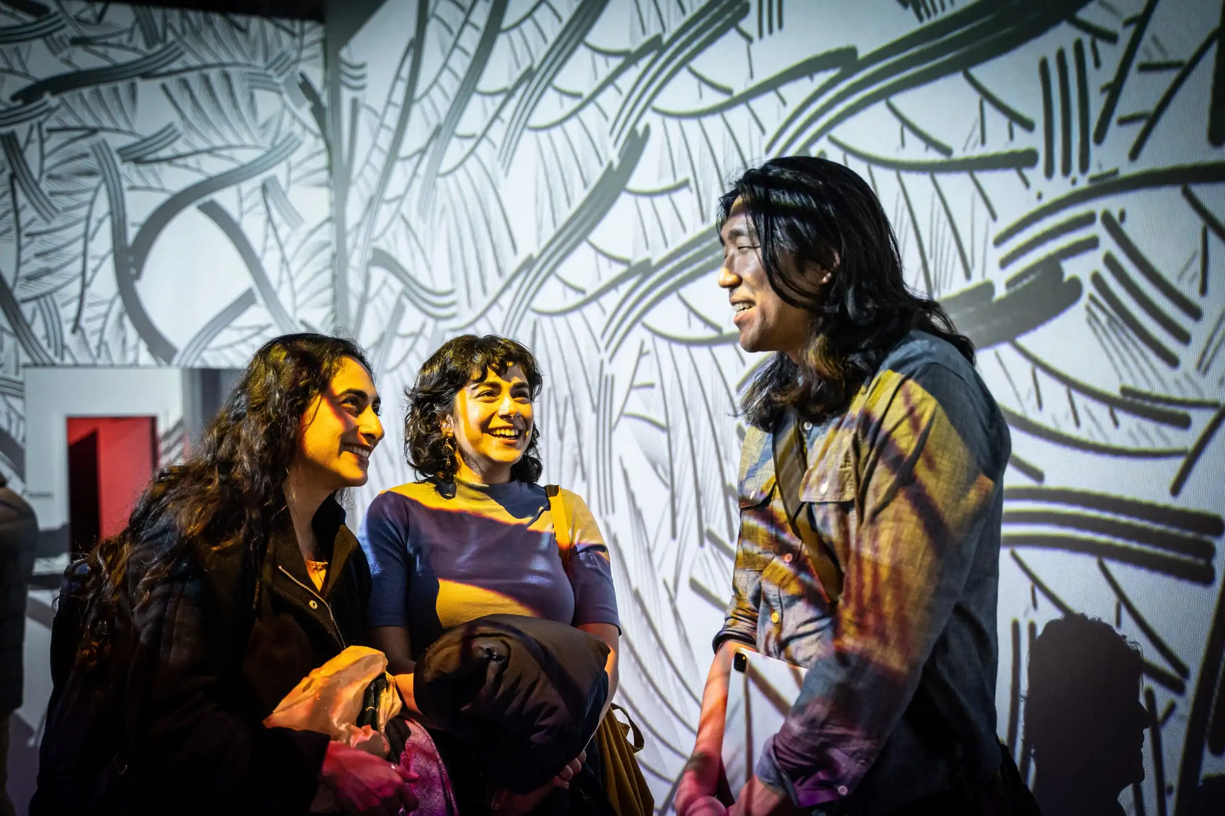 Visitors laughing in front of INTRICADA projected on the wall, Lume Studios, New York.
