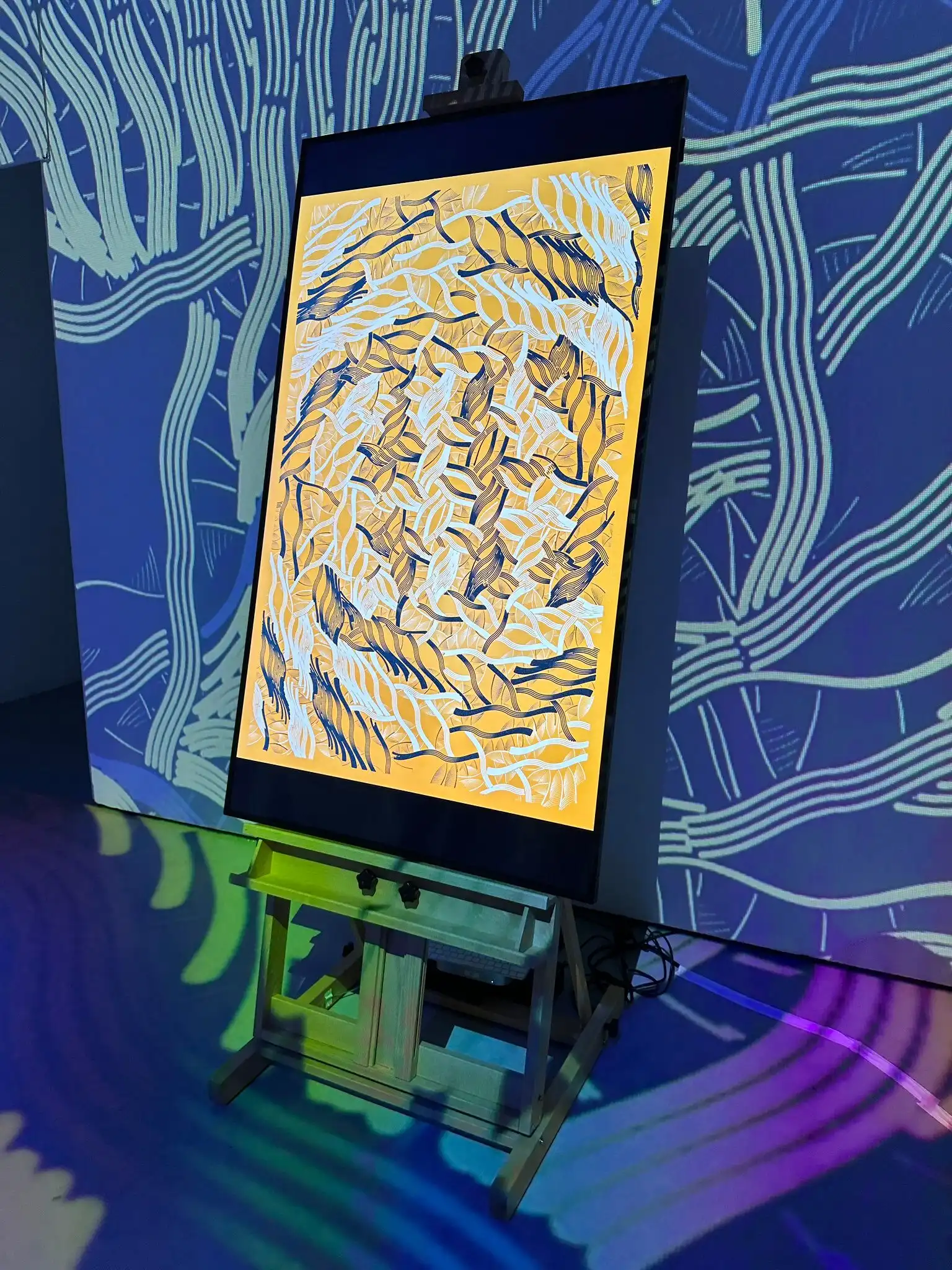 INTRICADA on a screen on an easel, surrounded by projected patterns, Lume Studios, New York.