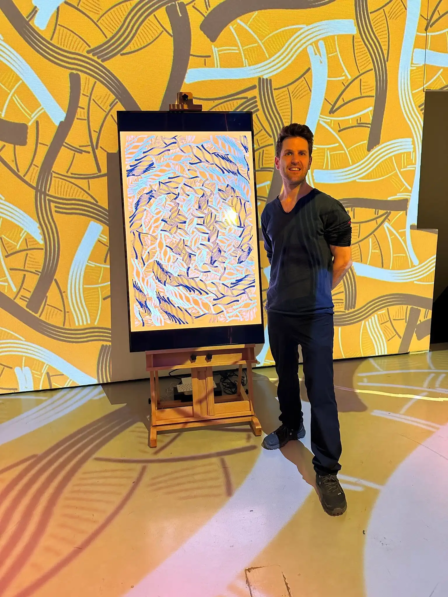 A visitor next to an INTRICADA screen on an easel, Lume Studios, New York.